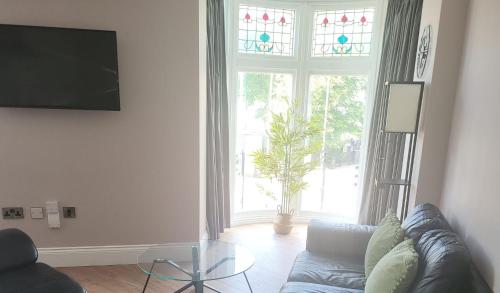 a living room with a couch and a large window at Harrogate Lifestyle Luxury Serviced ApartHotel in Harrogate