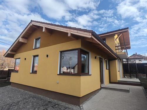 a yellow house with a large window on it at Jegenye apartments in Miercurea-Ciuc