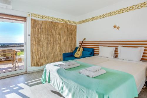 ein Schlafzimmer mit einem Bett mit Gitarre drauf in der Unterkunft Lovely Apart with Balcony - Beach FL by LovelyStay in Cabanas de Tavira