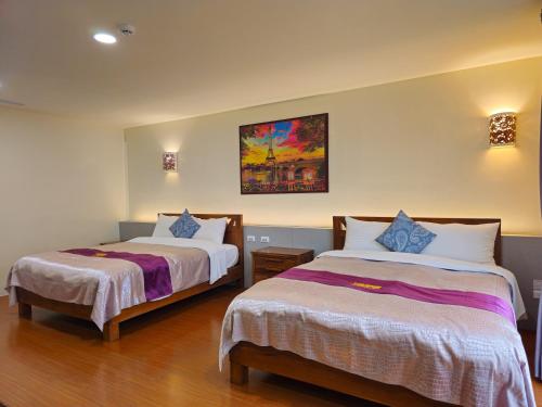 a bedroom with two beds and a painting on the wall at Kenting Garden Homestay in Kenting