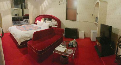 a room with a bed and a couch and a television at ロビンホテルRobin Hotel in Yachimata