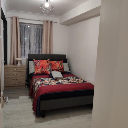 a bedroom with a bed with a red comforter at Stunning 2-Bed Apartment in London Dagenham in Dagenham