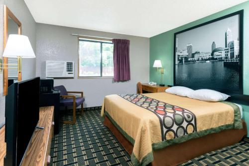 a hotel room with a bed and a large screen at Super 8 by Wyndham Twinsburg/Cleveland Area in Twinsburg