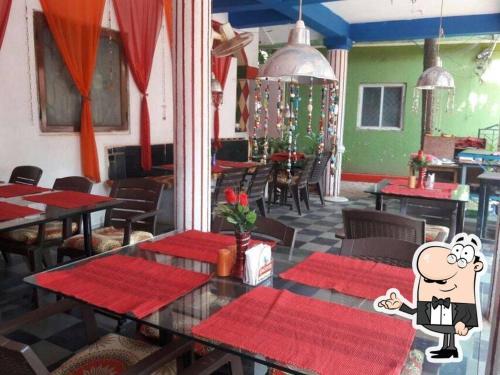 un restaurante con mesas y sillas rojas y una caricatura en Nestled in heart of the city en Calcuta