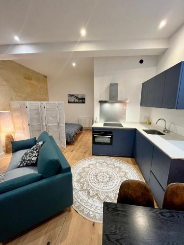 un salon avec un canapé bleu et une cuisine dans l'établissement Grand studio Loft Vieux Bordeaux, à Bordeaux