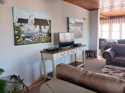 a living room with a couch and a desk with a television at Vergezicht Upper Unit in Franskraal