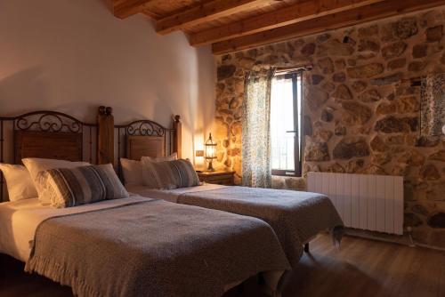 1 dormitorio con 2 camas y pared de piedra en Arialdegi en San Marcos