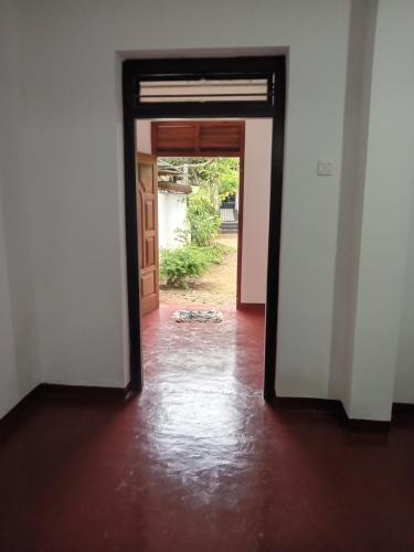 an open door into a room with a red floor at Villa 147 in Hikkaduwa