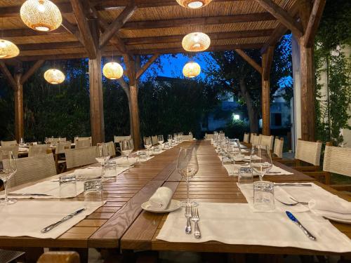 una larga mesa de madera con platos blancos y cubiertos en Residence Altair - Serra Degli Alimini 3 en Otranto