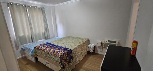 a small bedroom with a bed and a window at Apartamento praia centro itapema in Itapema