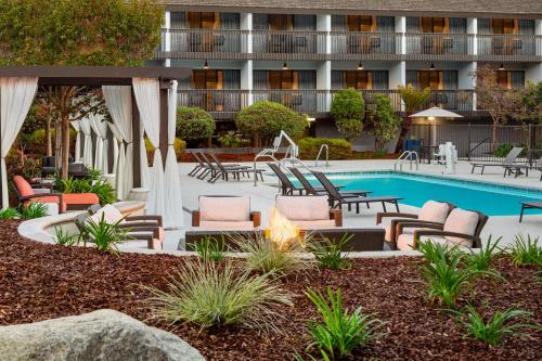 a resort pool with lounge chairs and a fire pit at Hilton Garden Inn Monterey in Monterey