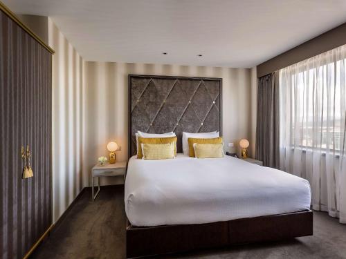 a bedroom with a large white bed with yellow pillows at Sofitel Wellington in Wellington