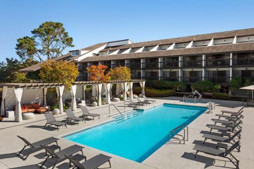 a hotel with a pool and chairs and a building at Hilton Garden Inn Monterey in Monterey
