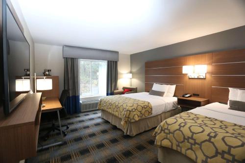 a hotel room with two beds and a desk at Baymont by Wyndham Lithia Springs Atlanta in Lithia Springs