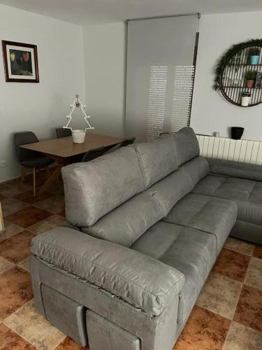 uma sala de estar com um sofá cinzento e uma mesa em Apartamento 7 adultos em Rueda