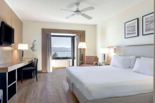 een hotelkamer met een bed, een bureau en een raam bij NH Bariloche Edelweiss in Bariloche