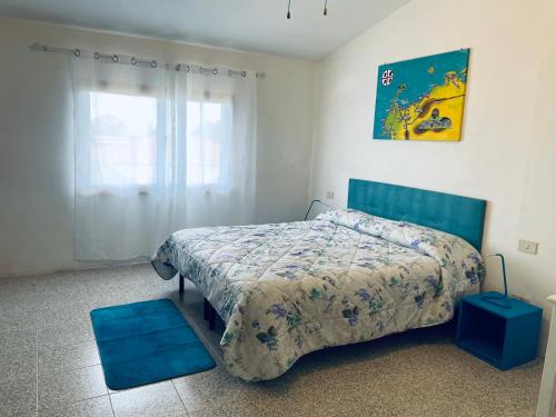 Schlafzimmer mit einem Bett mit blauem Kopfteil in der Unterkunft Portion of villa with garden, about 1km from the beach in Marina di Sorso