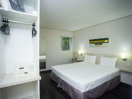 una camera d'albergo con letto bianco e bagno di ibis Styles Belem Nazare a Belém