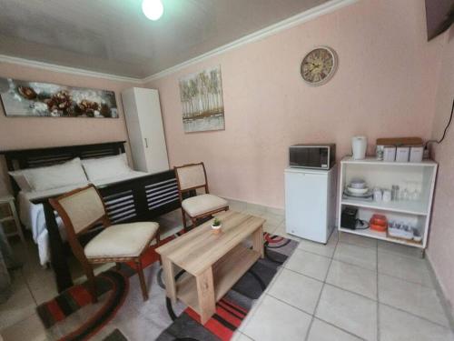 uma pequena sala de estar com uma cozinha com uma mesa e uma cama em Private outside room with own bathroom em Joanesburgo