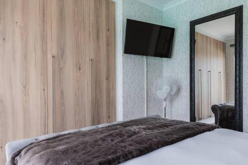 a bedroom with a bed with a mirror and a television at Pax's Luxury Romantic Penthouse on the Lagoon in Pretoria
