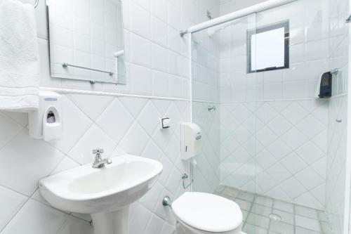 瓜拉圖巴的住宿－Hotel Caieiras，白色的浴室设有水槽和卫生间。