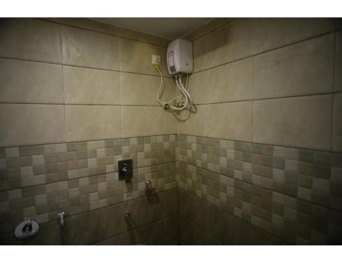 uma casa de banho em azulejo com um chuveiro e um telefone na parede em Hotel Royal Residency, Vadodara em Vadodara