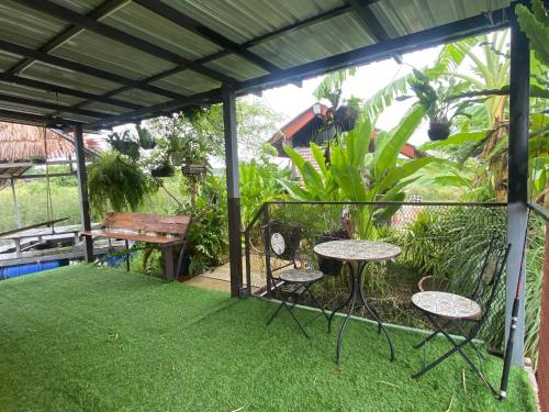 a patio with two tables and chairs on grass at บ้านอัญชัน 