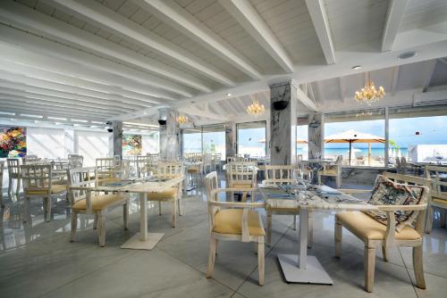 a dining room with tables and chairs and windows at Cavomarina Beach- Adults Only in Kavos