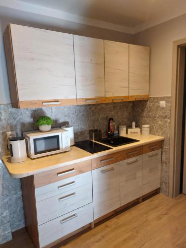 eine Küche mit weißen Schränken und einer Mikrowelle in der Unterkunft Lawendowy zakątek in Graboszyce
