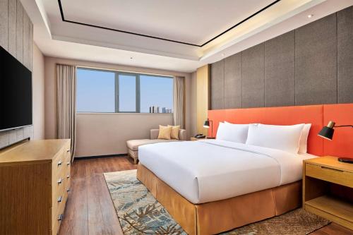 a hotel room with a bed and a television at Hilton Garden Inn Wuhan Hankou in Wuhan