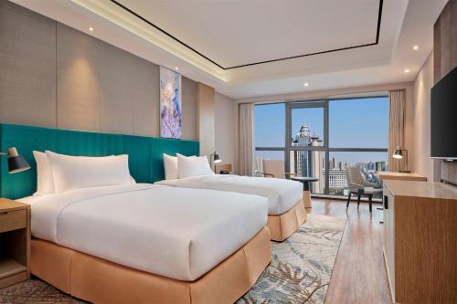 two beds in a hotel room with a view at Hilton Garden Inn Wuhan Hankou in Wuhan