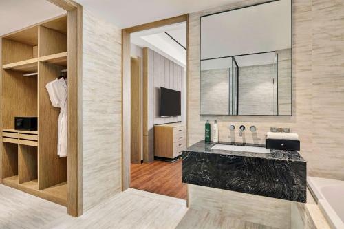 a bathroom with a tub and a sink and a mirror at Hilton Garden Inn Wuhan Hankou in Wuhan