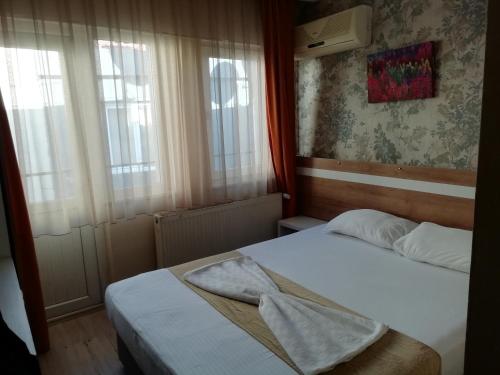 a small bedroom with two beds and two windows at Grand Ece Hotel in Çanakkale