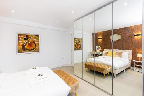 a bedroom with two beds and a glass wall at Luxury 3BR Flat, Parking & Garden, NW London in London