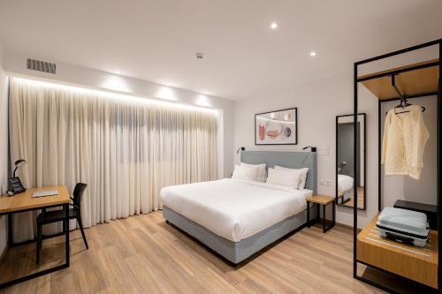 a bedroom with a bed and a desk and a television at Earos Urban Living in Athens