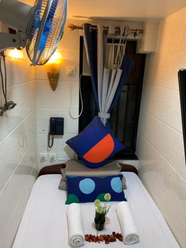 a room with a bed with a pillow and a fan at International Inn in Hong Kong