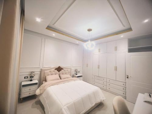 a white bedroom with a large bed and white cabinets at Villa Pasha Tirane in Tirana