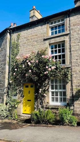 a brick building with a yellow door and a window at Charming Coates Cottage in Baslow