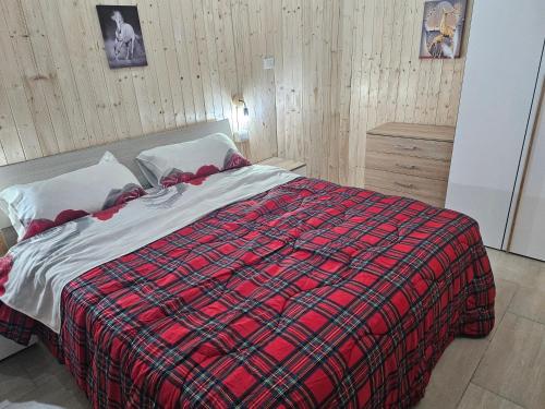 a bedroom with a bed with a red plaid blanket at ROMEO2 in Somma Lombardo