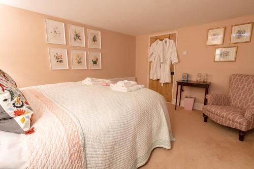 a bedroom with a white bed and a chair at Charming Coates Cottage in Baslow