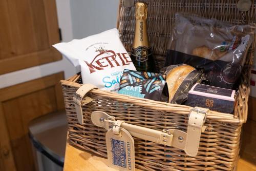 a basket filled with food and a bottle of beer at Charming Coates Cottage in Baslow