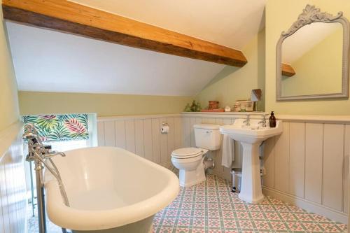 a bathroom with a sink and a tub and a toilet at Charming Coates Cottage in Baslow