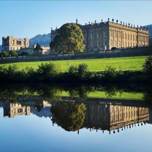 a large building with its reflection in a body of water at Charming Coates Cottage in Baslow