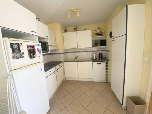 une cuisine avec des armoires blanches et un réfrigérateur blanc dans l'établissement AS24091- P3 Dans un secteur calme avec parking privé, au Grau-du-Roi