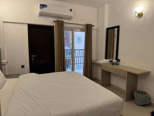 a bedroom with a bed and a desk and a window at Hamsun Apart Hotel Clifton in Karachi