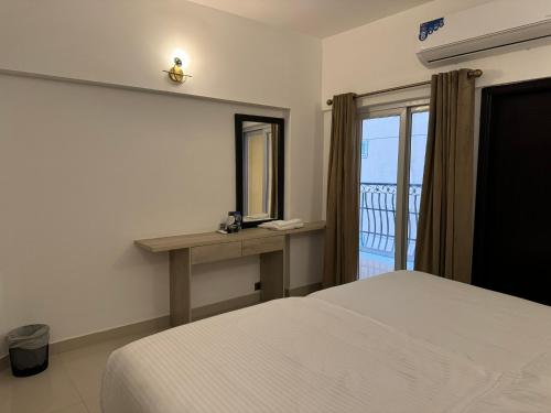 a bedroom with a bed and a mirror and a window at Hamsun Apart Hotel Clifton in Karachi