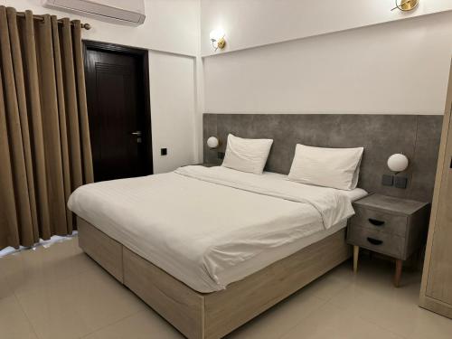 a bedroom with a large bed with white sheets and pillows at Hamsun Apart Hotel Clifton in Karachi