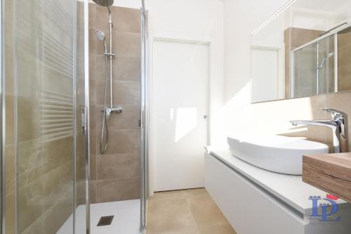 y baño con ducha y lavabo blanco. en DesenzanoLoft Smeraldo Family apartment en Desenzano del Garda
