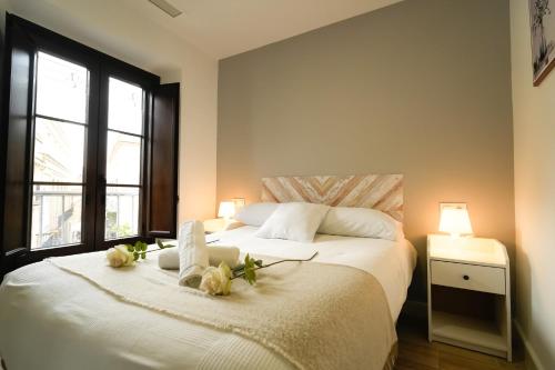 Un dormitorio con una cama blanca con flores. en Apartamentos Consistorio Live, en Jerez de la Frontera