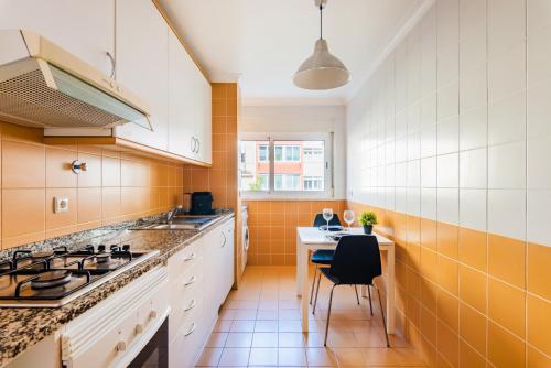 uma cozinha com armários laranja e branco e uma mesa em Olaias Flat (with Free Parking) em Lisboa